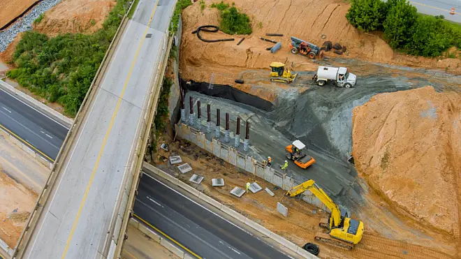 Bauingenieure auf einer Brückenbaustelle nutzen Tablet und mobile Ingenieurbau-Software zur digitalen Projektsteuerung.